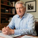 Portrait d'un homme âgé et déterminé assis à son bureau, symbolisant le courage face à la maladie et l'engagement humanitaire